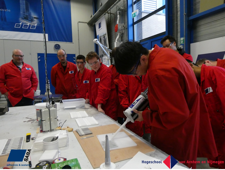 Verschillende scholieren van de HAN in rode overalls werken met SABA producten 