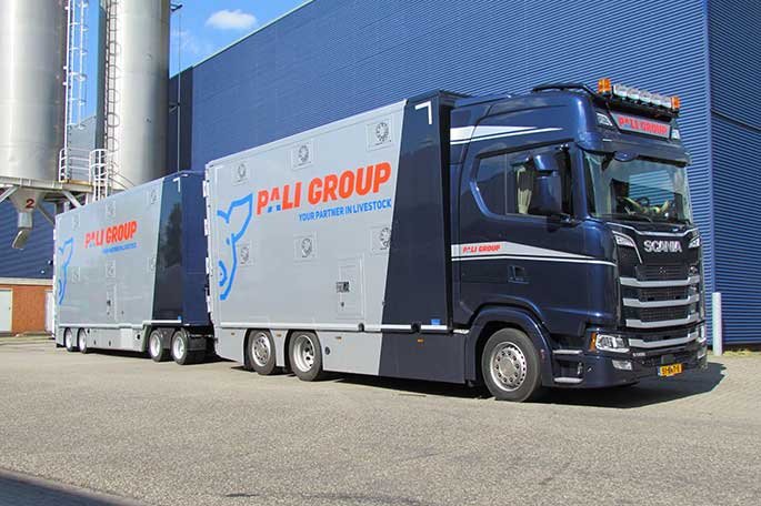 Zwart/grijze vrachtwagen voor een blauw bedrijfspand