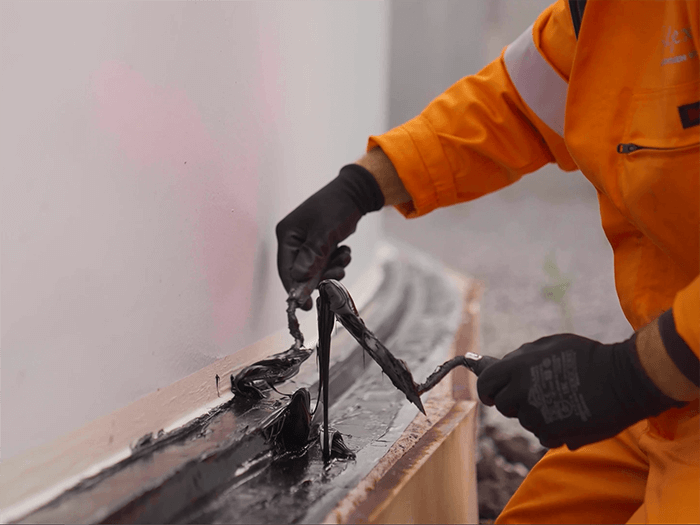 Man in oranje overall brengt SABA sealflex aan op rand van witte silo