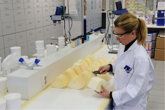 Vrouw met laboratoriumjas en veiligheidsbril controleert maten met een schuifmaat