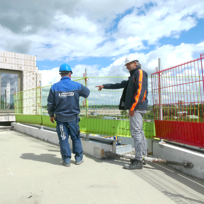 Twee mensen in bouwkleding op dak van gebouw