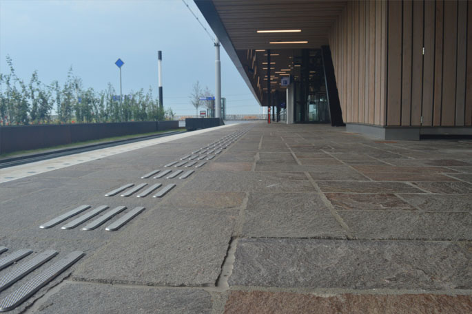 Perron van Nederlands station met in voorgrond voelbare lijnen op begin spoor aan te geven