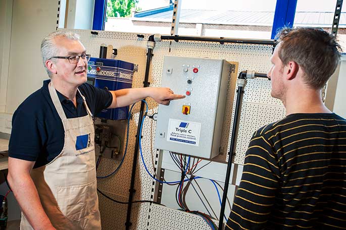 Een werknemer van SABA laat knoppen van machine aan iemand zien