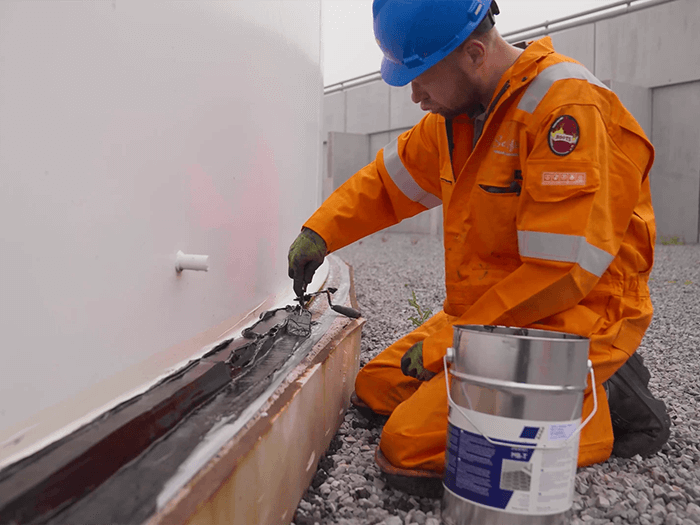 Man in oranje overall brengt SABA sealflex aan op rand van witte silo